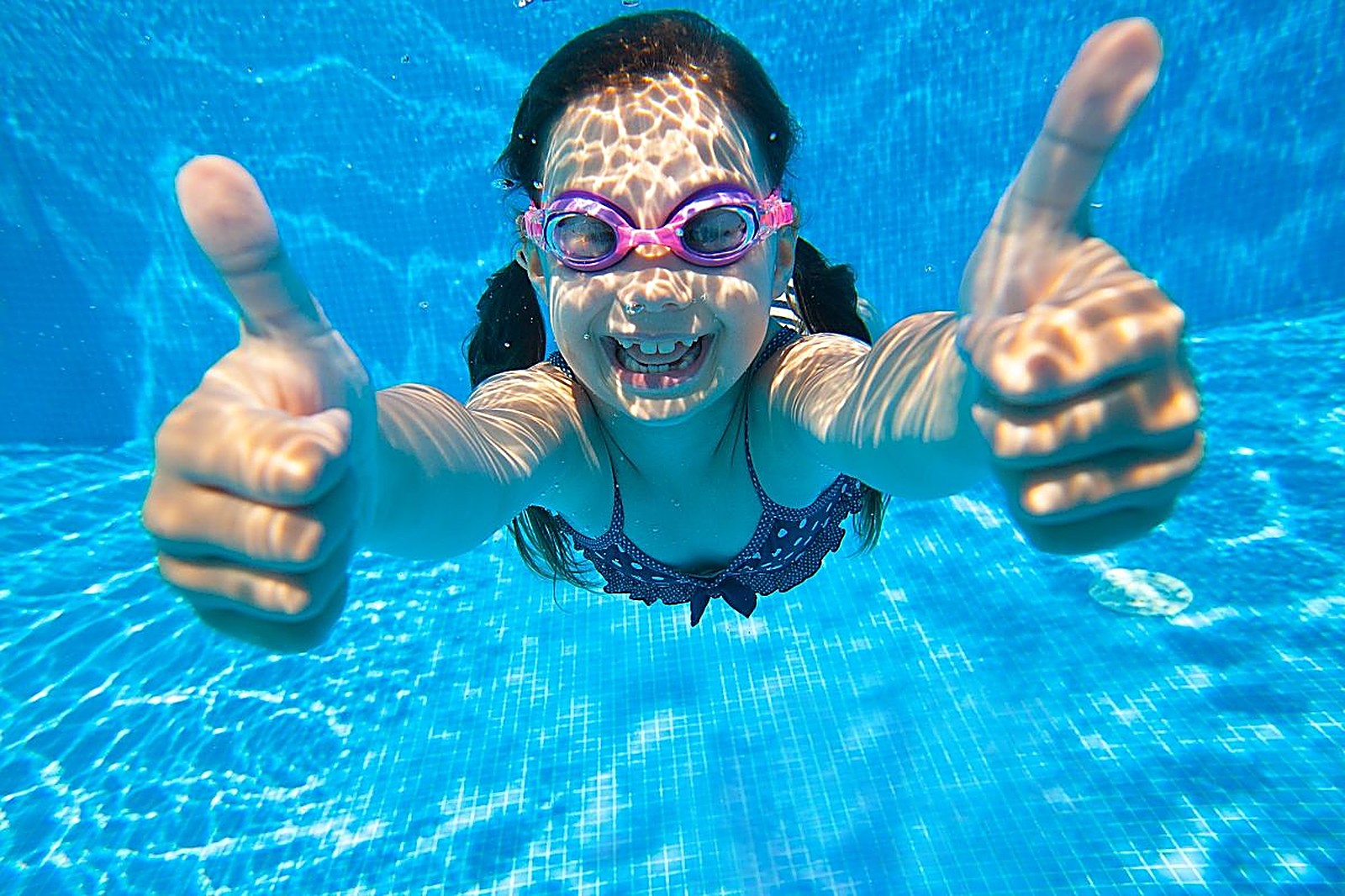 Child giving thumbs-up underwater